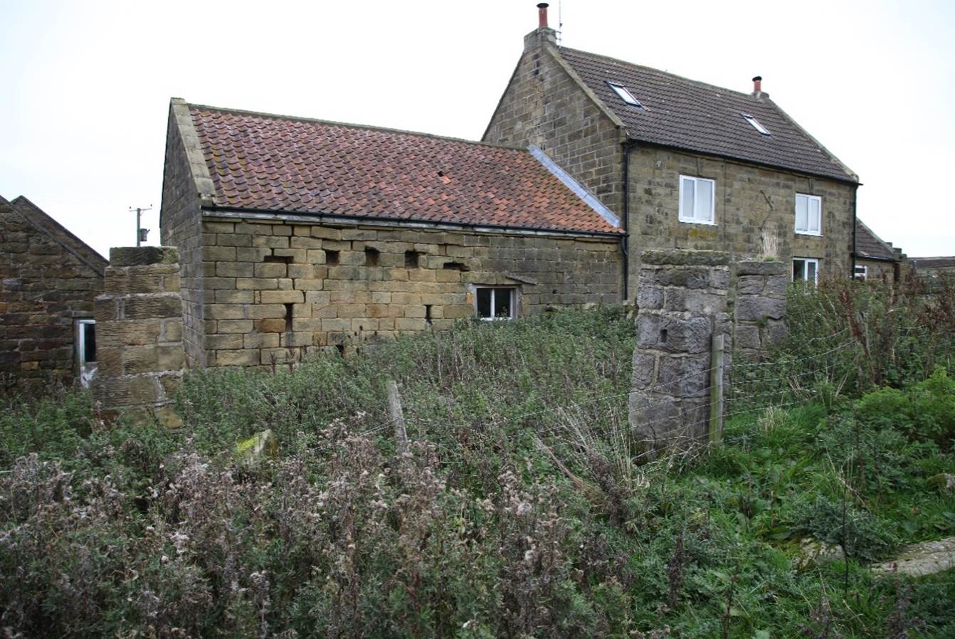 A stone house with a stone wall
Description automatically generated